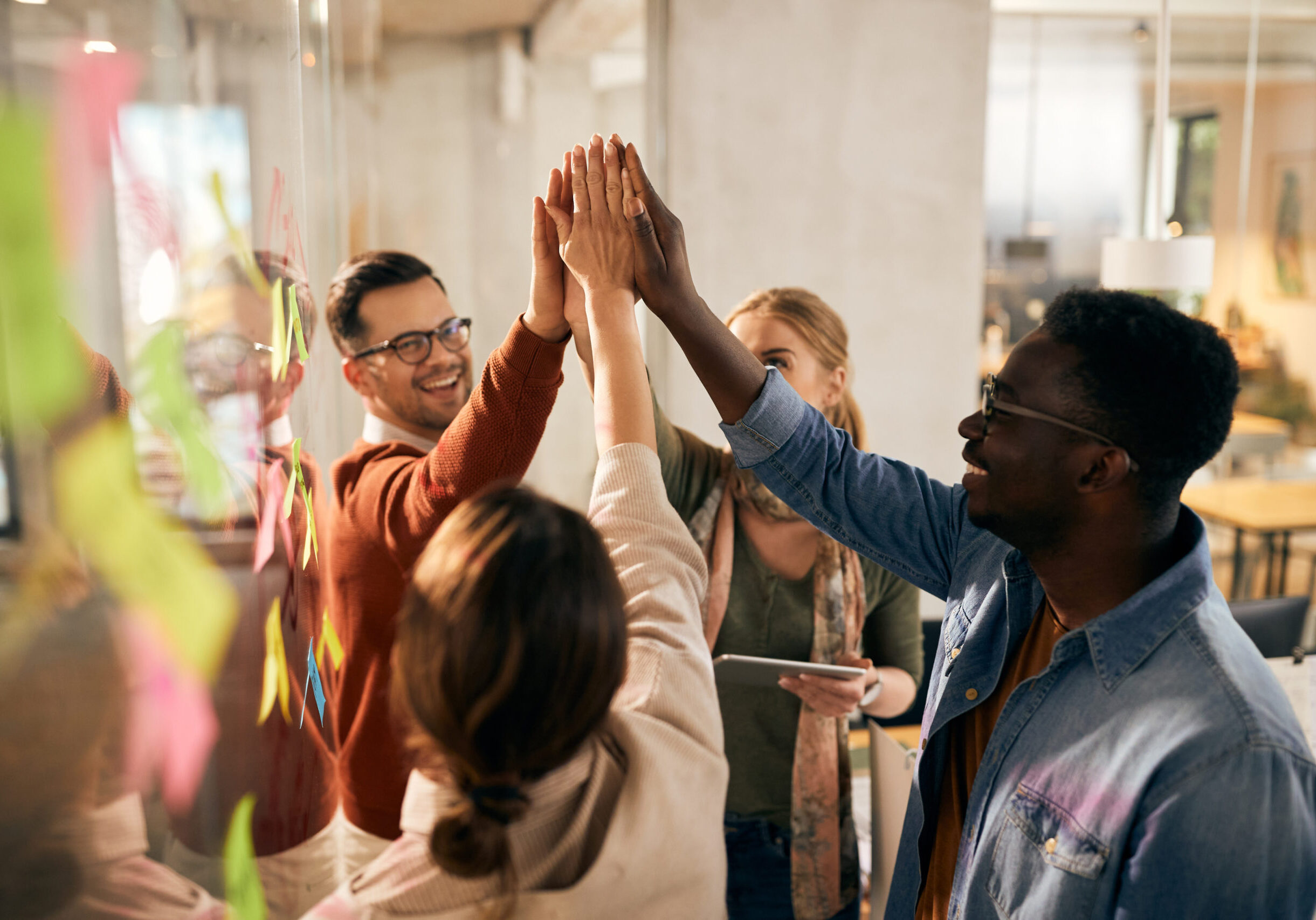 Happy multi-ethnic start-up team uniting their hands during business meeting at casual office.